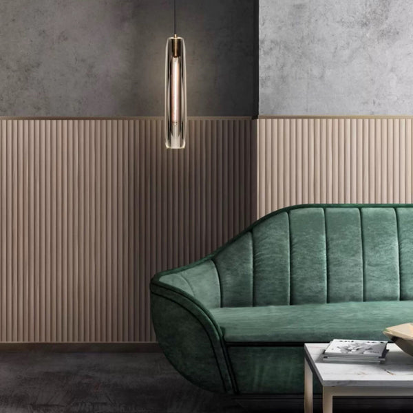 Green sofa in a modern room with a pendant light and textured wall.