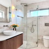 Modern bathroom with glass shower enclosure, wooden vanity, and white fixtures.
