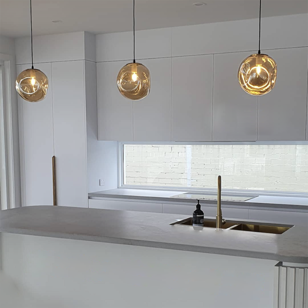 modern queensland island bench in slate grey with 3 hamilton amber glass pendant lights hanging over amber glass