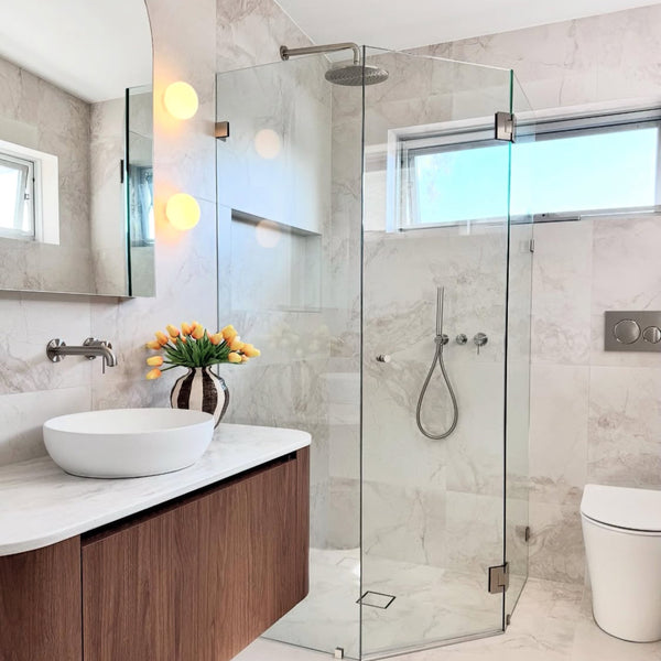 Modern bathroom with glass shower enclosure, wooden vanity, and white fixtures.