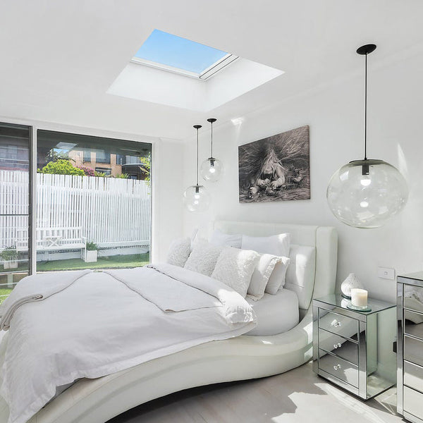 Modern bedroom with a skylight, round bed, and glass nightstands with clear glass pendant lights black accents