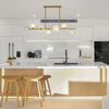 Modern kitchen with white island, bar stools, and sleek appliances. Luxury brushed brass linear chandelier